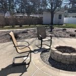 This is a close up of the recent landscaping service in goffstown nh. This shows a cleanly laid fire pit with rocks surrounding it. Two chairs sit at the fire pit ready to be used.