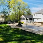 Second photo of Hooksett NH landscaping job, showing the rest of the backyard. There is an inground pool, freshly trimmed grass borders the pool.