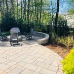 Recently finished hooksett nh landscaping job performed. Left side includes a patio including a fire pit. Pruning service in Hooksett NH also completed. Patio is extended to the end of the yard. A black fence borders the edge of the lawn.