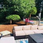 This image shows a patio set up with a garden bed in the rear. There is a pool to the right side. We provide many of our customer lawn care services in Manchester NH. This image shows what this Manchester NH project looks like finished!